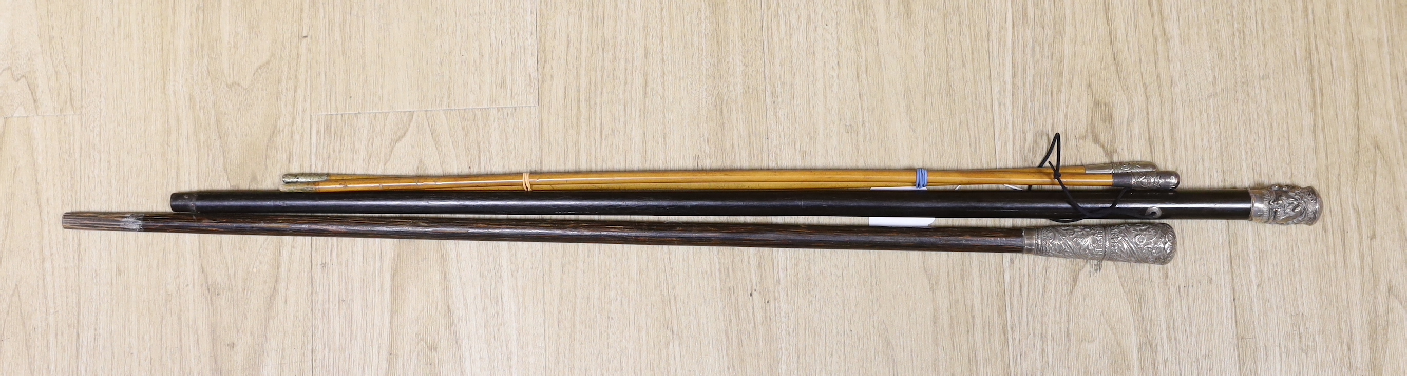 Two Indian embossed silver tipped walking sticks and two Burmese police swagger sticks (4)